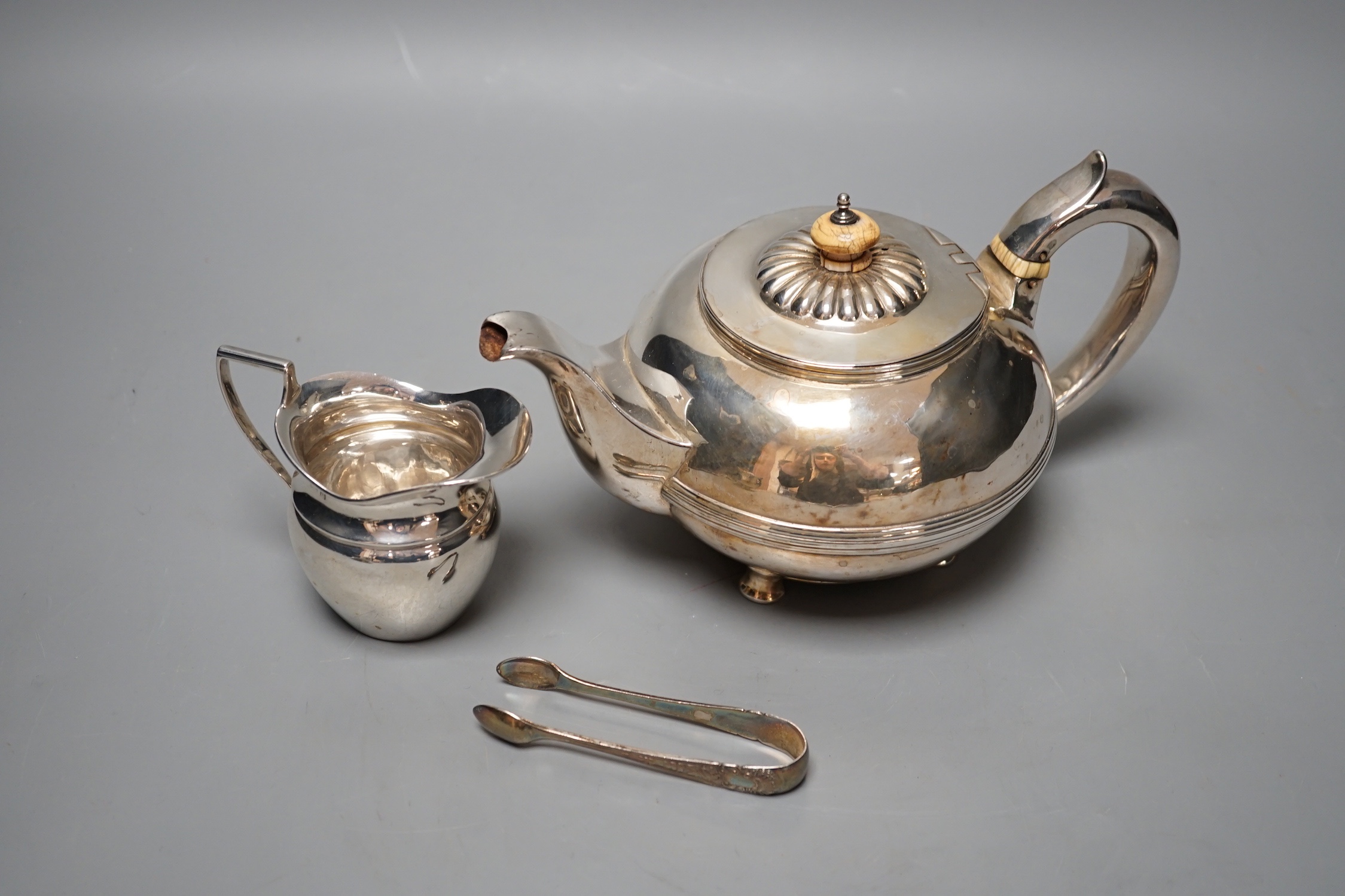 A George IV silver circular teapot, Craddock & Reid, London, 1824, a later silver cream jug and pair of silver sugar tongs, gross 19oz.